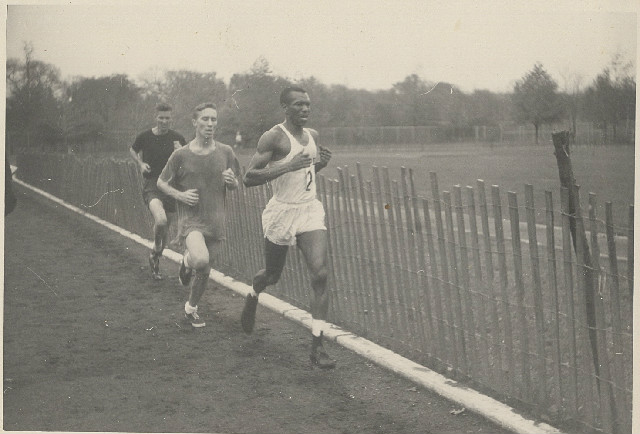 Ted Corbitt Running Near a Wooden Fence