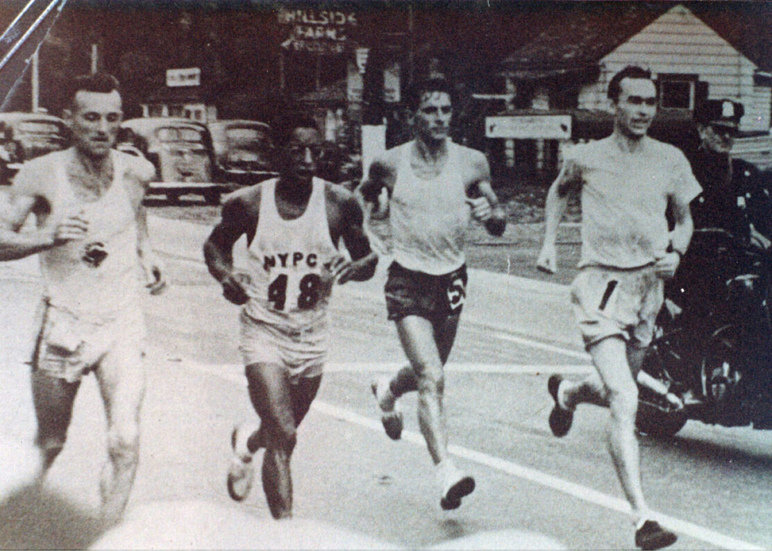 Four runners racing down a city street